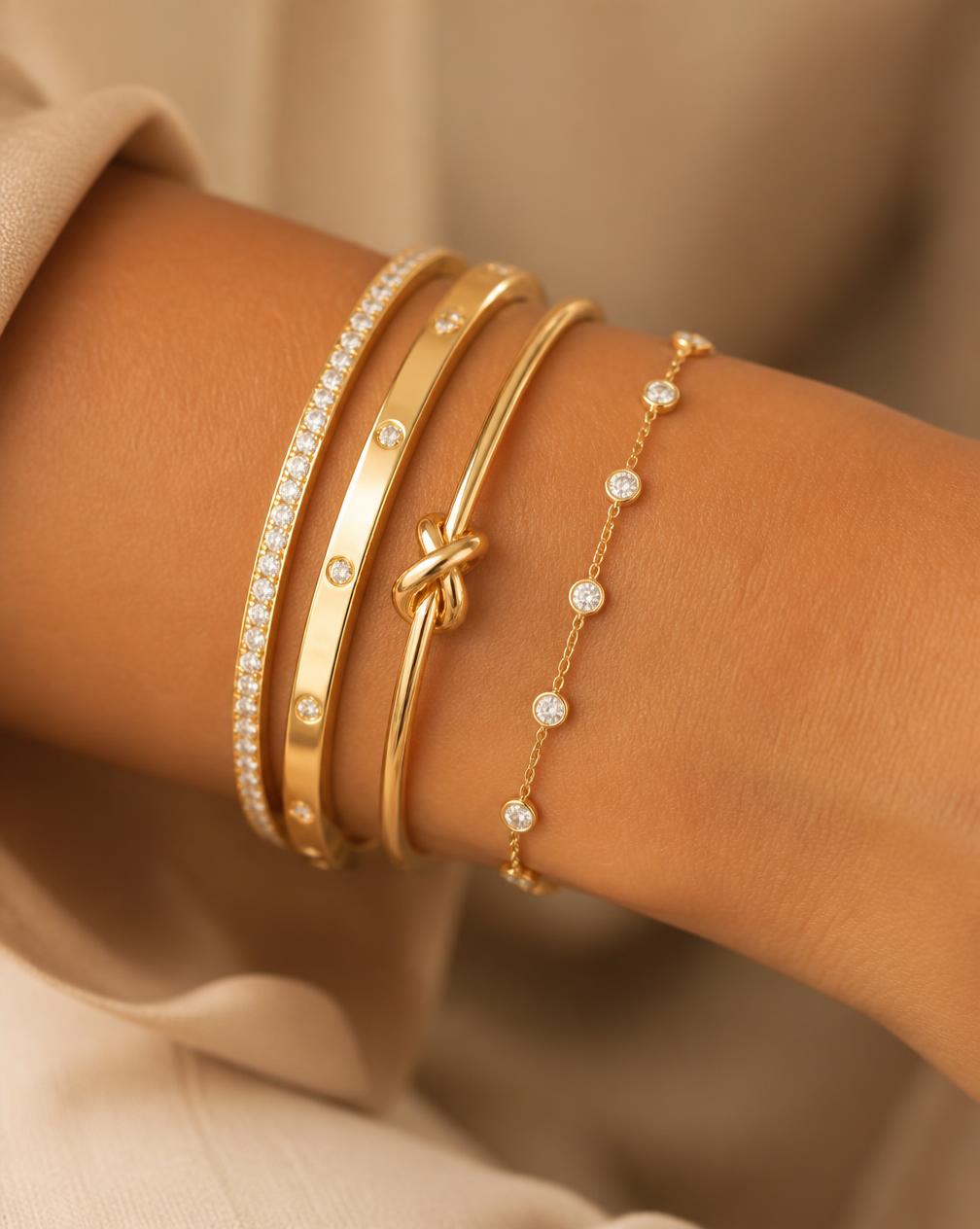 Stacked gold bangles and a diamond bracelet on a wrist
