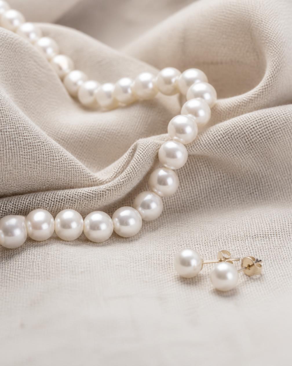 Lustrous pearl necklace and pearl studs on soft beige linen